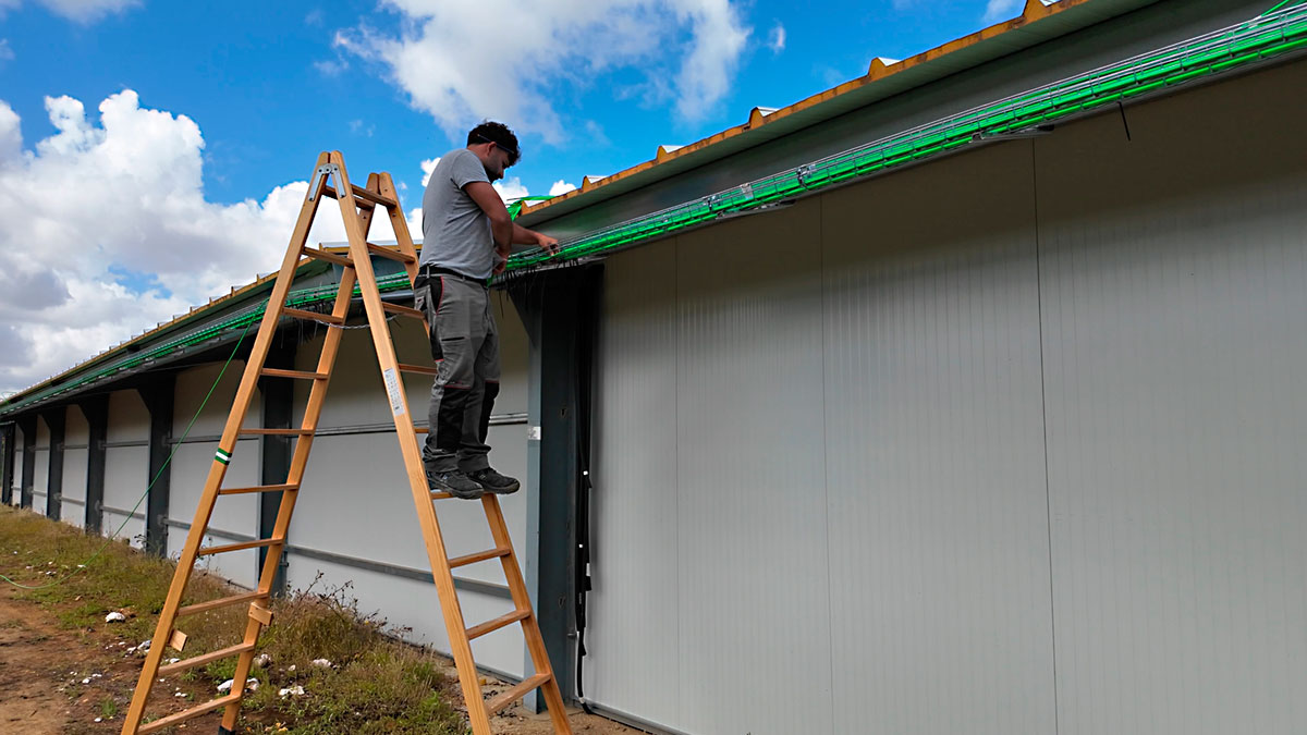 Técnico en escalera instalando bandeja en alero